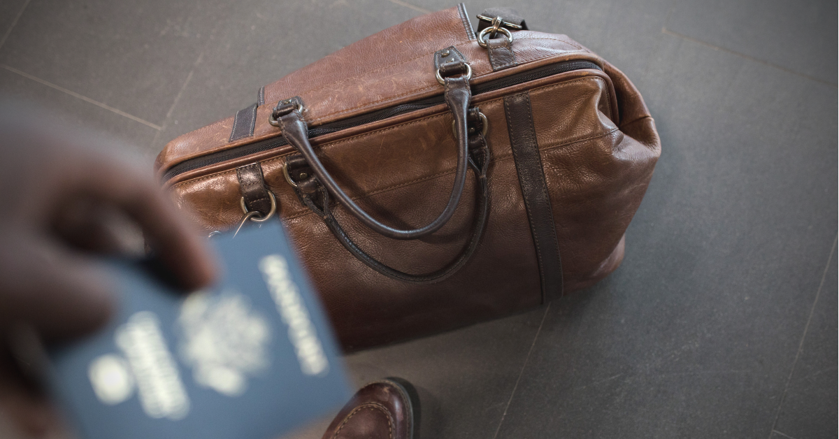 Someone with a passport and a leather travel bag